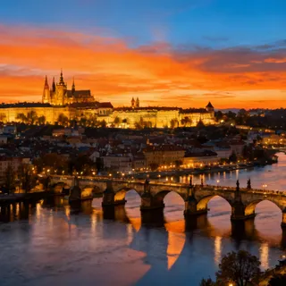 A sweeping panoramic sunset view of Prague, Czech Republic, showing the Vltava River, Charles Bridge, and the massive, illuminated Prague Castle complex perched on a hill, against an orange and blue sky. Professional photography, high dynamic range.