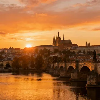Panorama view of Prague Castle complex on a hill overlooking the Vltava River at sunset